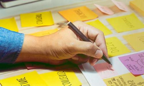 Project Manager with Graduate Certificate Taking Notes on Post-it Note 