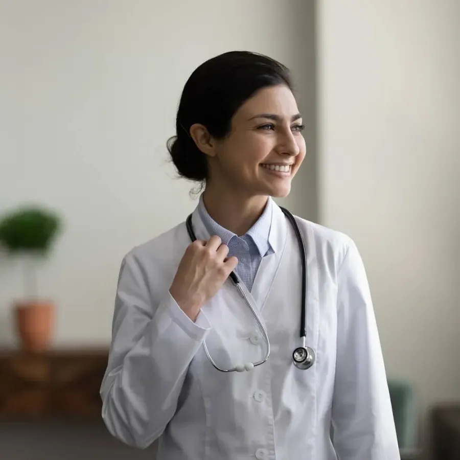 Woman nurse practitioner who graduated with MSN degree smiling in clinic